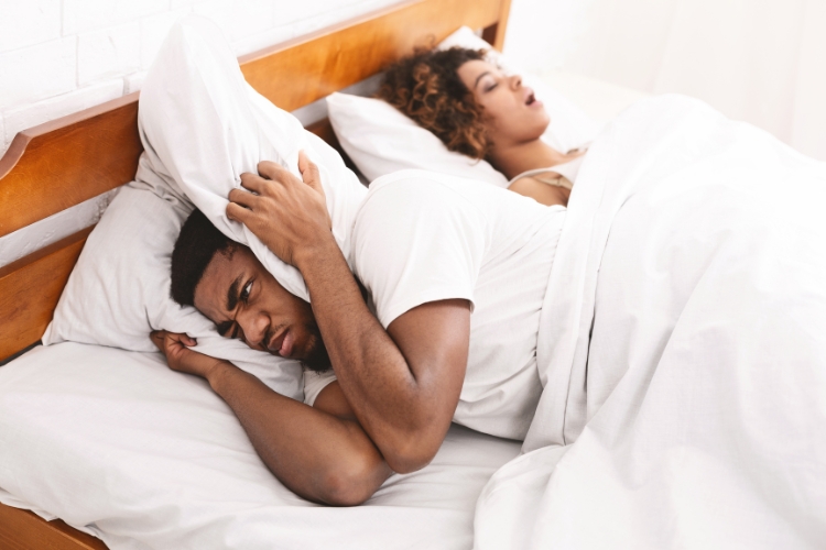 young man trying to stop wife snoring with pillow