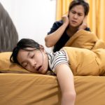 girl putting hand son ears to listening sis snoring sleep in side